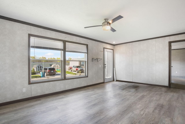 unfurnished room with ornamental molding, wood finished floors, a ceiling fan, and baseboards