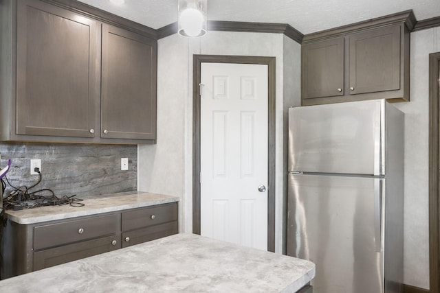 kitchen featuring freestanding refrigerator, light countertops, and dark brown cabinetry