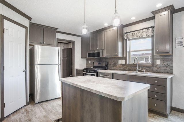 kitchen with stainless steel appliances, crown molding, a sink, light wood-style flooring, and decorative backsplash