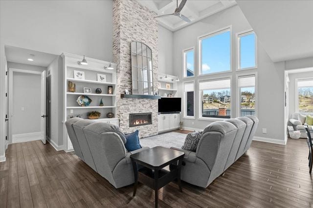 8353 Pier Point Ct, South Lyon, MI 48178 - living area featuring a towering ceiling, a fireplace, baseboards, dark wood-style flooring, and a ceiling fan