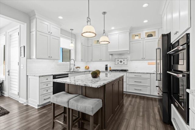 8353 Pier Point Ct, South Lyon, MI 48178 - kitchen with black appliances, a breakfast bar area, dark wood finished floors, a sink, and recessed lighting