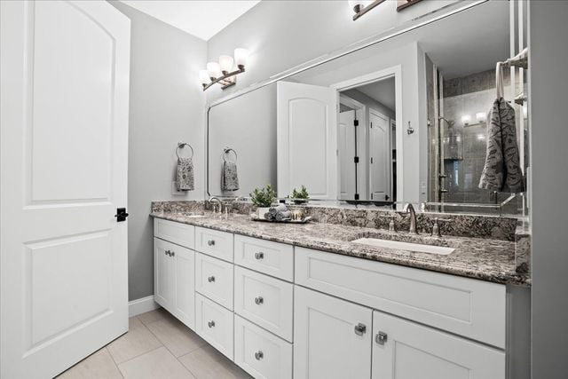 8353 Pier Point Ct, South Lyon, MI 48178 - full bathroom featuring double vanity, tiled shower, tile patterned floors, and baseboards