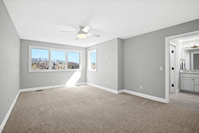 8353 Pier Point Ct, South Lyon, MI 48178 - unfurnished bedroom featuring light colored carpet, baseboards, and a ceiling fan