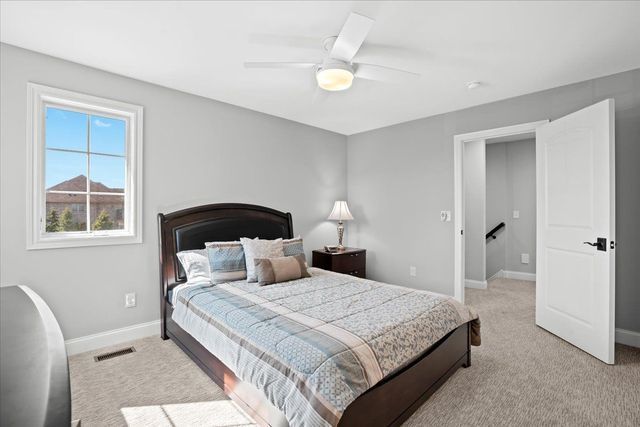 8353 Pier Point Ct, South Lyon, MI 48178 - bedroom featuring baseboards, light carpet, and ceiling fan