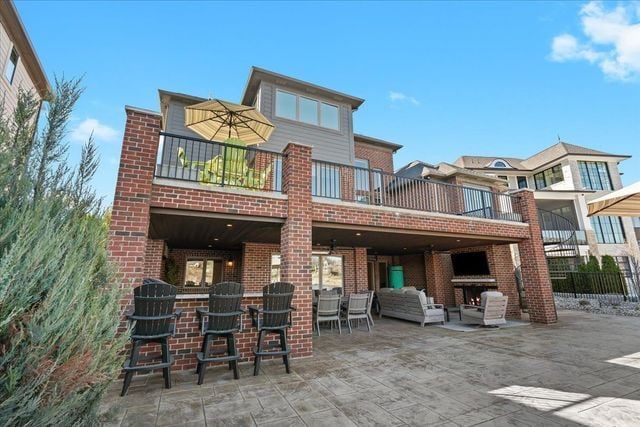 8353 Pier Point Ct, South Lyon, MI 48178 - back of property with a patio, brick siding, and a balcony