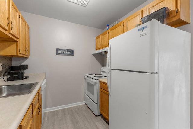 kitchen with white appliances, light wood-type flooring, a sink, light countertops, and under cabinet range hood