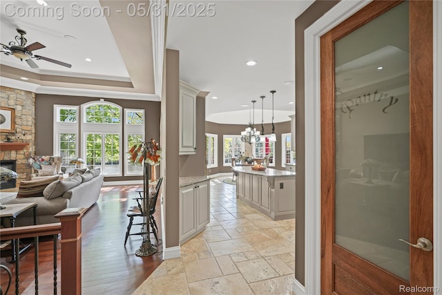 3074 Pond Rd, Leonard, MI 48367 - hall featuring recessed lighting, baseboards, stone tile flooring, a tray ceiling, and a chandelier