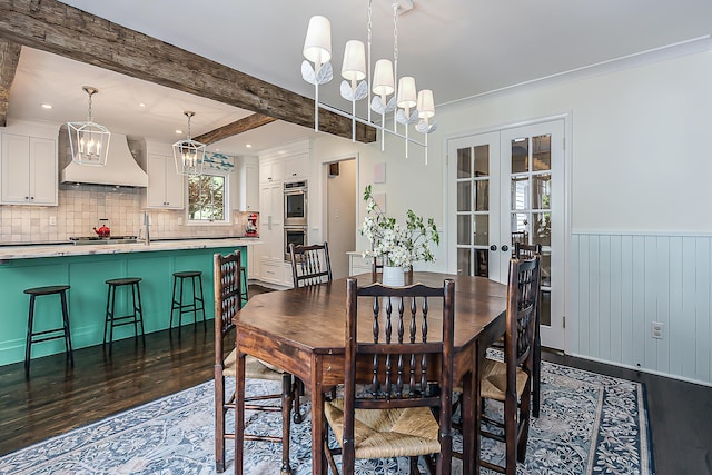 2124 Brockman Blvd, Ann Arbor, MI 48104 - dining area with a chandelier, dark wood-type flooring, a wainscoted wall, french doors, and beamed ceiling