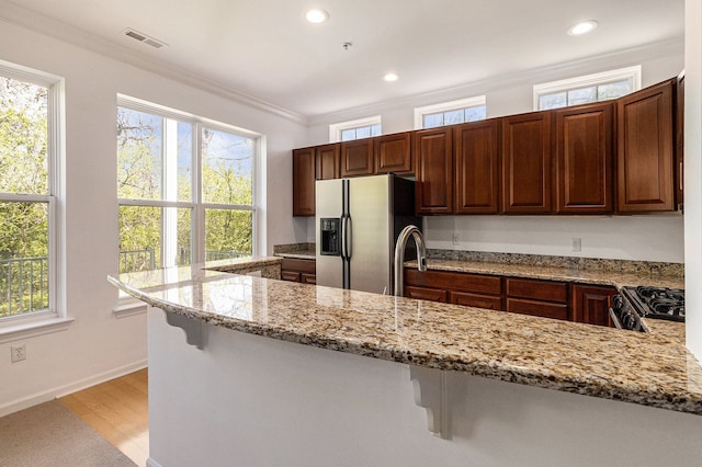 3203 Asher Rd, Ann Arbor, MI 48104 - kitchen with stainless steel fridge, gas stove, light stone counters, plenty of natural light, and recessed lighting