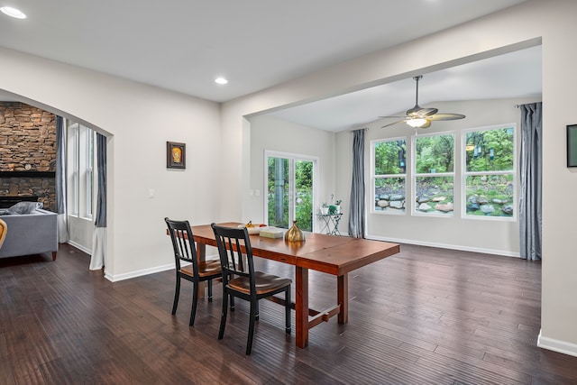 dining space with dark wood-style flooring, baseboards, ceiling fan, recessed lighting, and a stone fireplace