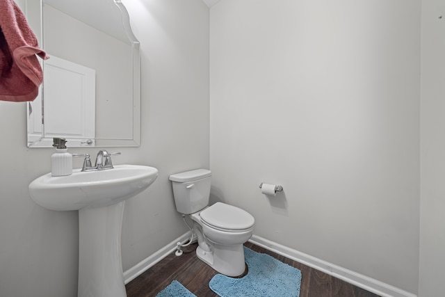 bathroom with baseboards, toilet, and wood finished floors