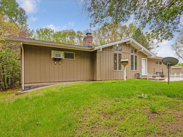 back of property featuring a chimney, a lawn, and board and batten siding
