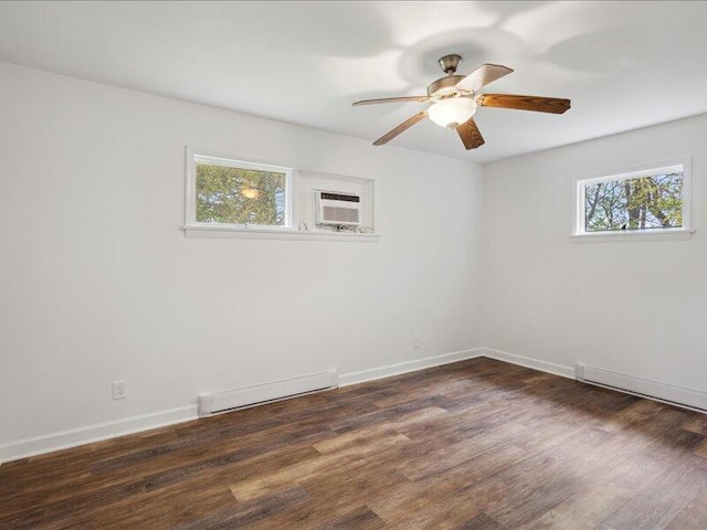 spare room with dark wood-style flooring, a ceiling fan, a wall unit AC, and baseboards