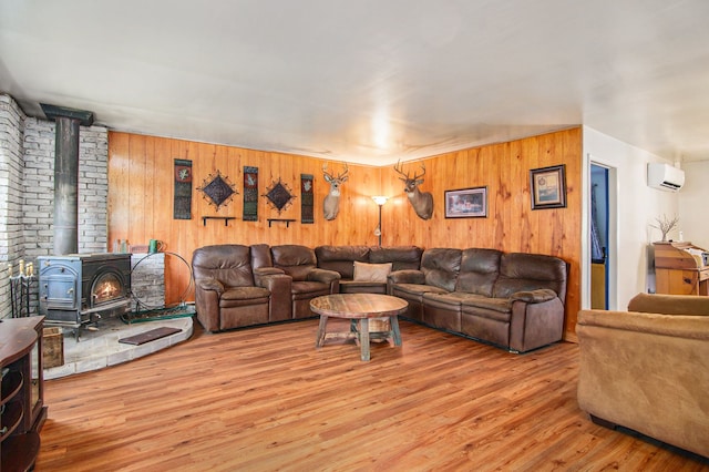 102 Franklin St, Holly, MI 48442 - living area featuring a wall unit AC, a wood stove, light wood finished floors, and wooden walls