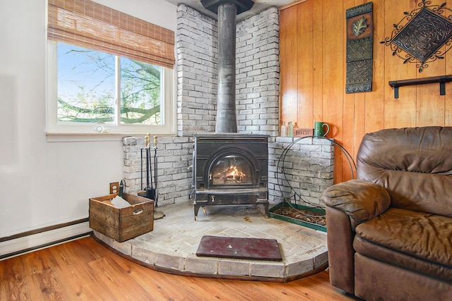 102 Franklin St, Holly, MI 48442 - sitting room with a wood stove, wood finished floors, baseboards, wood walls, and a baseboard radiator