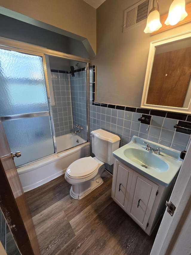 915 Cleophus Pkwy, Lincoln Park, MI 48146 - full bathroom featuring wood finished floors, toilet, vanity, enclosed tub / shower combo, and tile walls