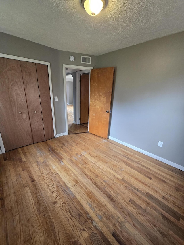 915 Cleophus Pkwy, Lincoln Park, MI 48146 - unfurnished bedroom with a textured ceiling, baseboards, wood finished floors, and a closet