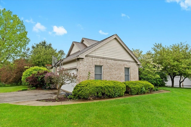 view of property exterior with a yard, an attached garage, brick siding, and driveway