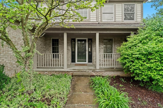 entrance to property with covered porch and brick siding