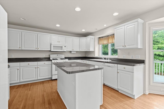 kitchen with white appliances, a sink, plenty of natural light, white cabinetry, and recessed lighting