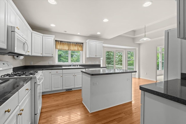 kitchen featuring white appliances, dark countertops, white cabinets, light wood finished floors, and recessed lighting