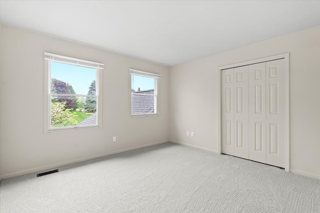 unfurnished bedroom with baseboards, light colored carpet, and a closet