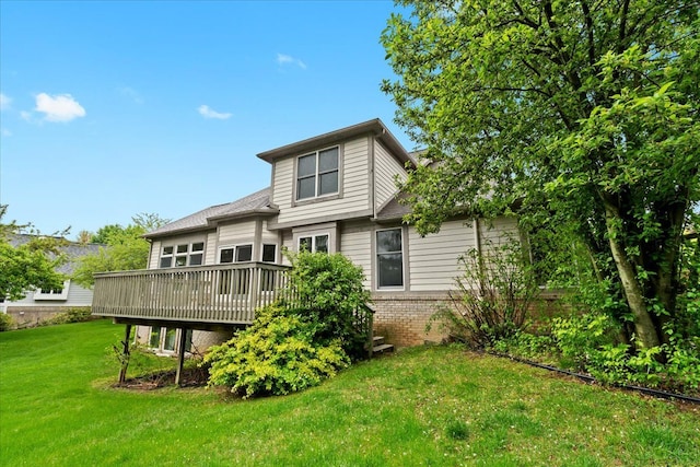 rear view of house featuring a wooden deck, brick siding, and a yard