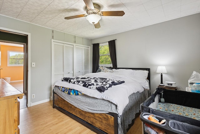 bedroom with wood finished floors, a closet, ceiling fan, and baseboards