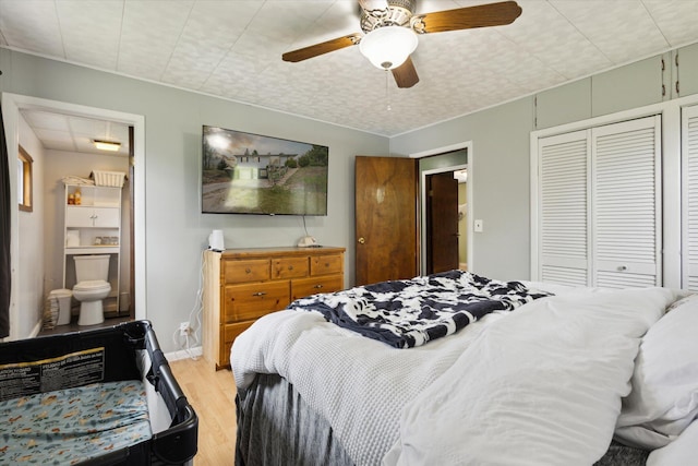 bedroom featuring light wood finished floors, a closet, ensuite bathroom, a ceiling fan, and baseboards