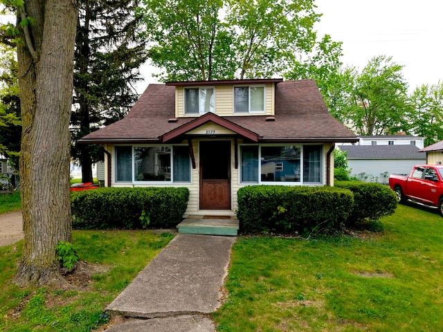 bungalow with a front lawn and a shingled roof