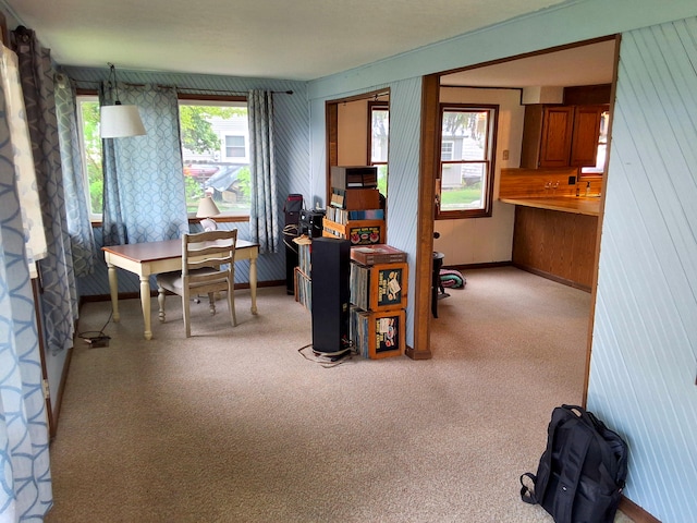 office featuring light carpet, wooden walls, baseboards, and wallpapered walls