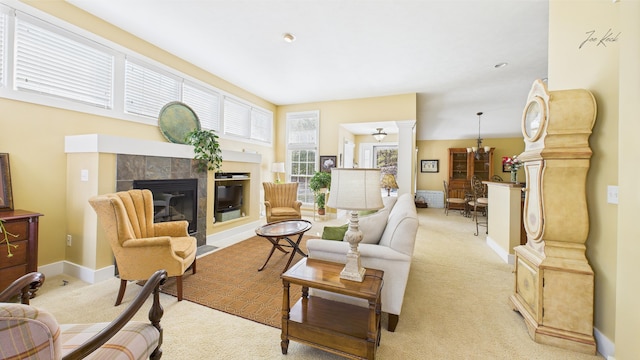 living room with ornate columns, light colored carpet, a tiled fireplace, and baseboards