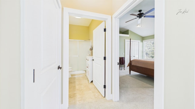 hall with vaulted ceiling, light colored carpet, baseboards, and light tile patterned floors
