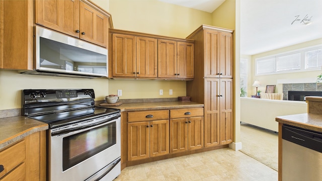 kitchen with stainless steel appliances, brown cabinets, and a fireplace