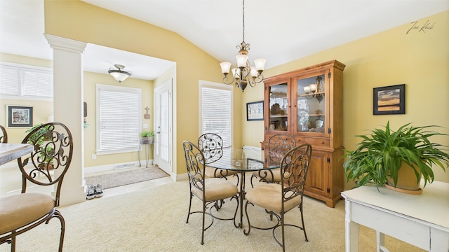 dining space featuring a chandelier, light colored carpet, lofted ceiling, and ornate columns