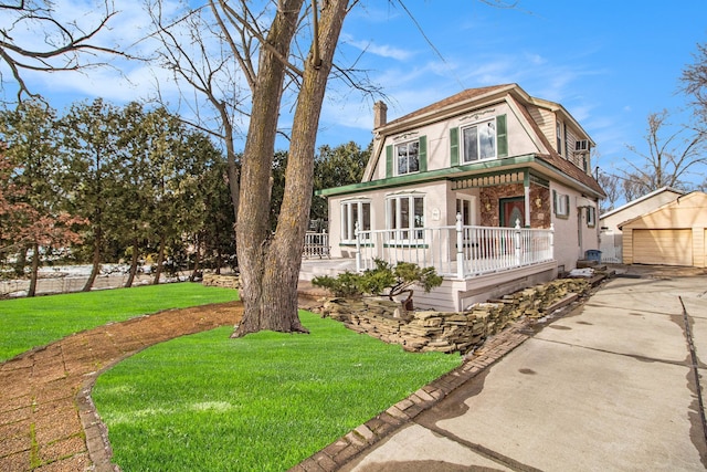 view of front of home with an outbuilding, a front lawn, a detached garage, and a chimney