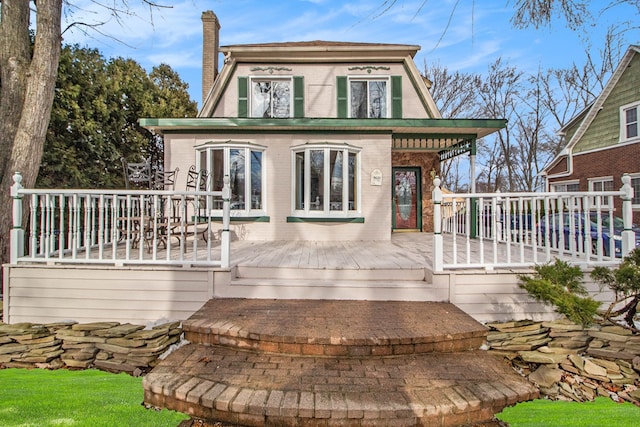 back of house with a chimney, brick siding, and a wooden deck