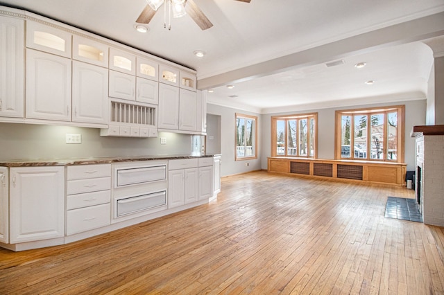 kitchen with light wood-style floors, a ceiling fan, white cabinetry, a brick fireplace, and glass insert cabinets