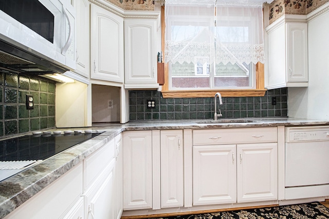 kitchen featuring white appliances, a sink, white cabinets, and tasteful backsplash