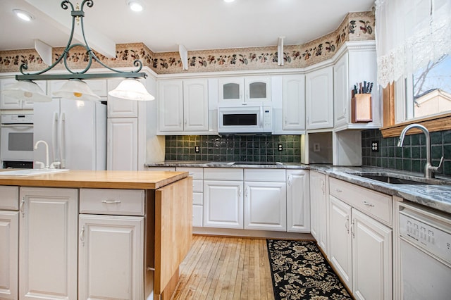 kitchen with white appliances, a sink, butcher block countertops, white cabinets, and recessed lighting