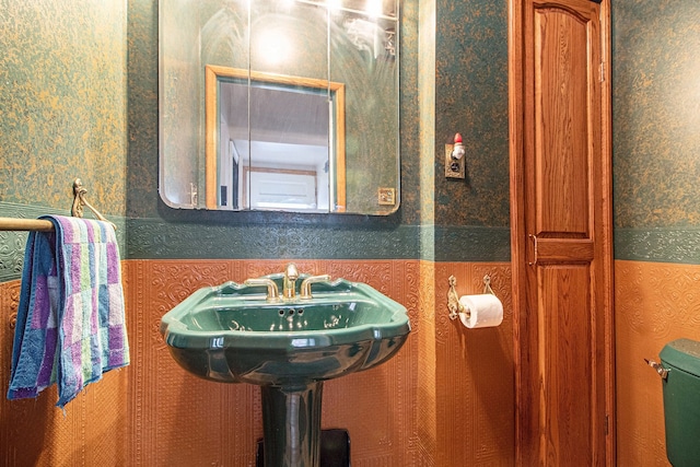 half bath featuring wallpapered walls and toilet