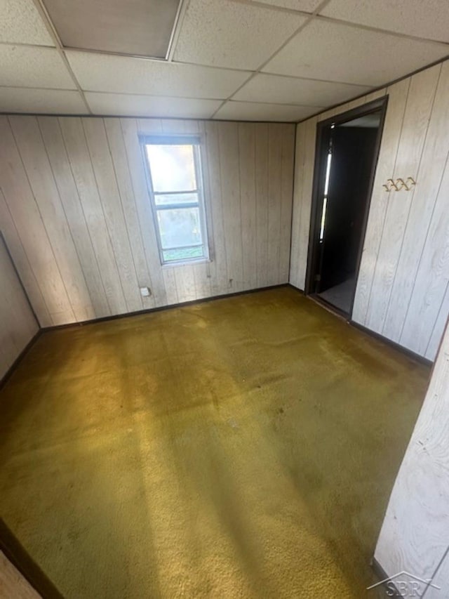 spare room featuring a drop ceiling and wooden walls