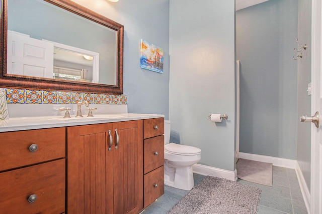 bathroom featuring toilet, baseboards, vanity, and tile patterned flooring