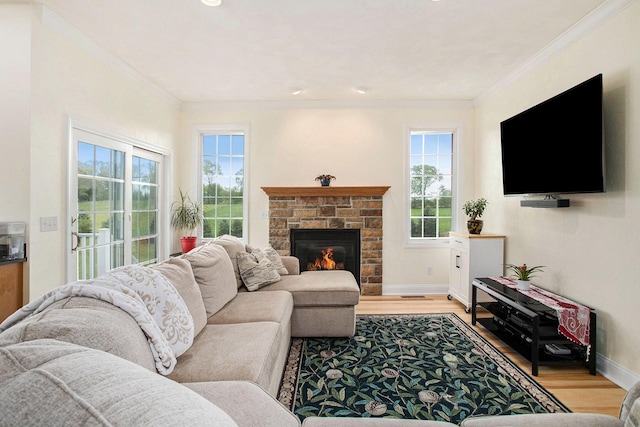 living area featuring healthy amount of natural light, light wood-style floors, baseboards, ornamental molding, and a stone fireplace