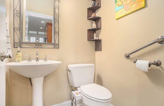 half bath featuring toilet and baseboards