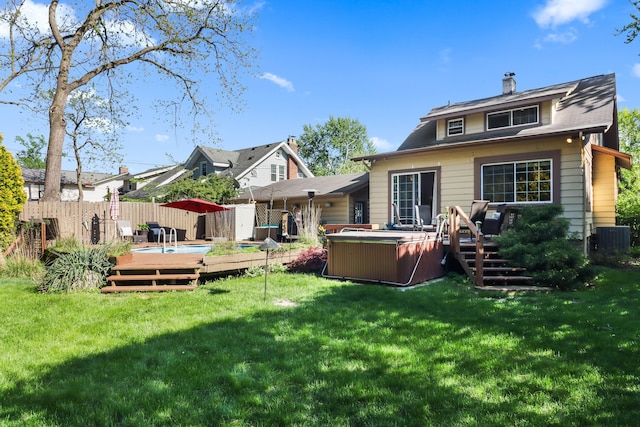 rear view of house featuring a deck, central air condition unit, a hot tub, and a chimney