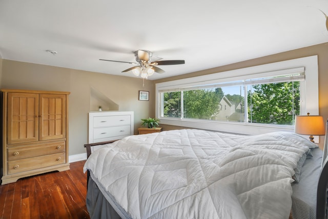 bedroom with dark wood finished floors, a ceiling fan, and baseboards