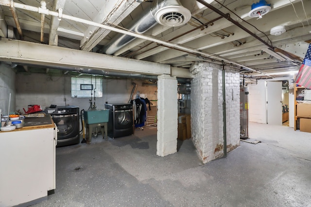 basement featuring water heater, washing machine and clothes dryer, a sink, and fridge