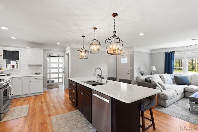 4730 Occidental Hwy, Adrian, MI 49221 - kitchen featuring appliances with stainless steel finishes, a sink, open floor plan, a barn door, and light wood-type flooring