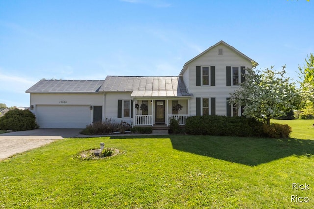 colonial inspired home featuring covered porch, driveway, a front yard, an attached garage, and a standing seam roof